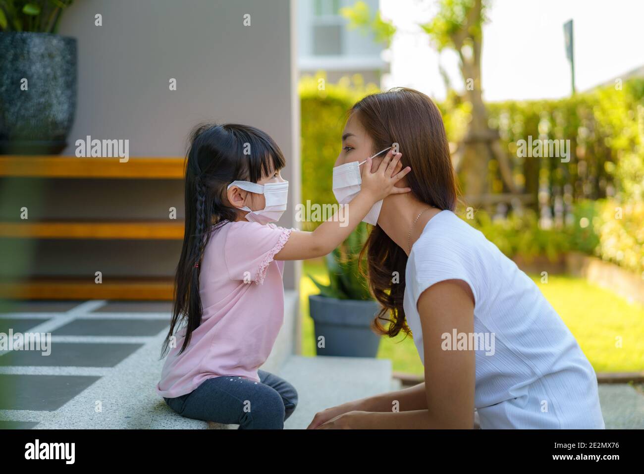La fille asiatique aide sa mère à porter un masque de protection pour protéger la situation d'épidémie de coronavirus Covid-19 avant d'aller à l'école. Préparez-vous à goélette Banque D'Images
