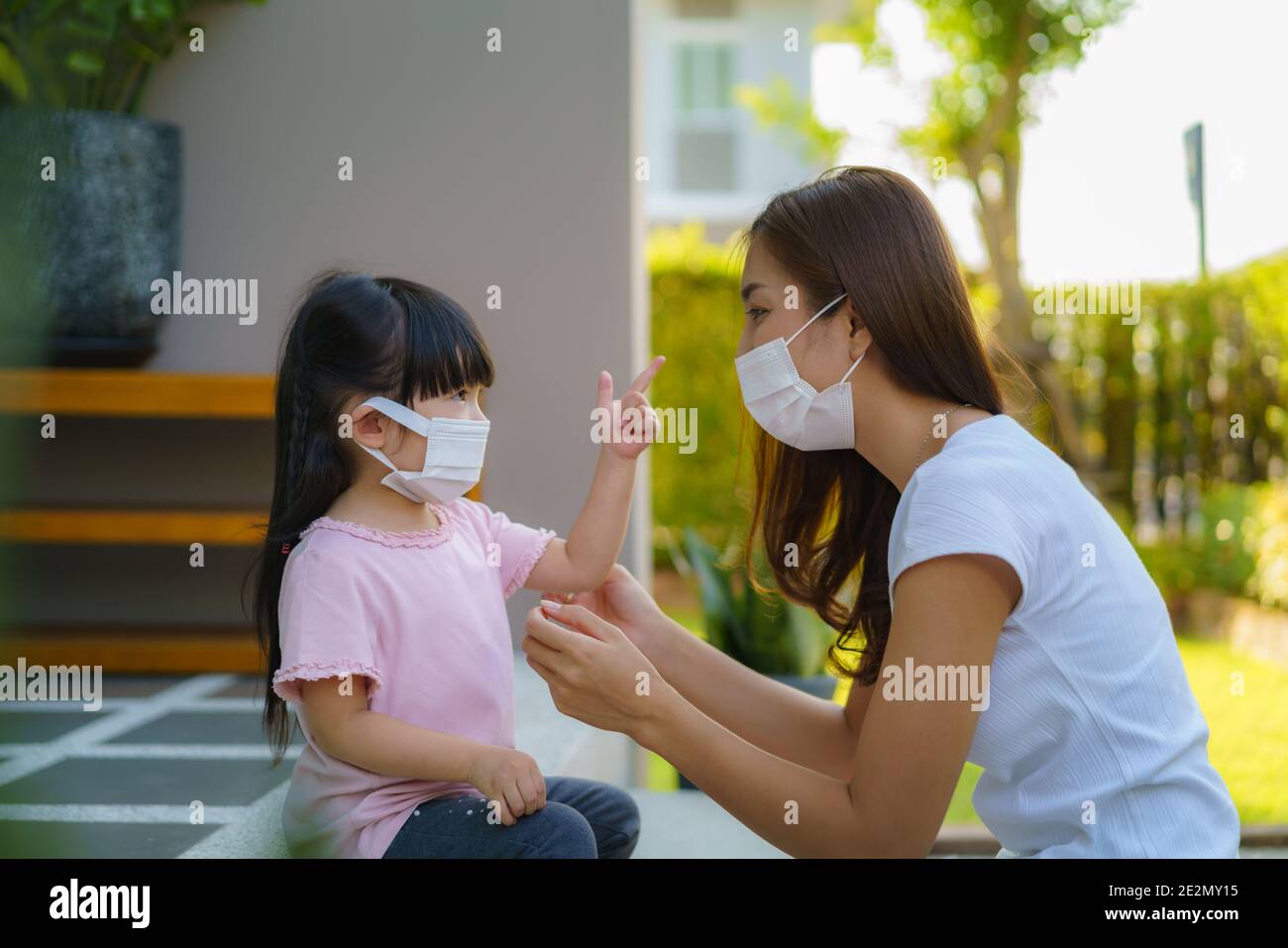 La mère asiatique aide sa fille à porter un masque de protection pour protéger la situation d'épidémie de coronavirus Covid-19 avant d'aller à l'école. Préparez-vous à l'école Banque D'Images