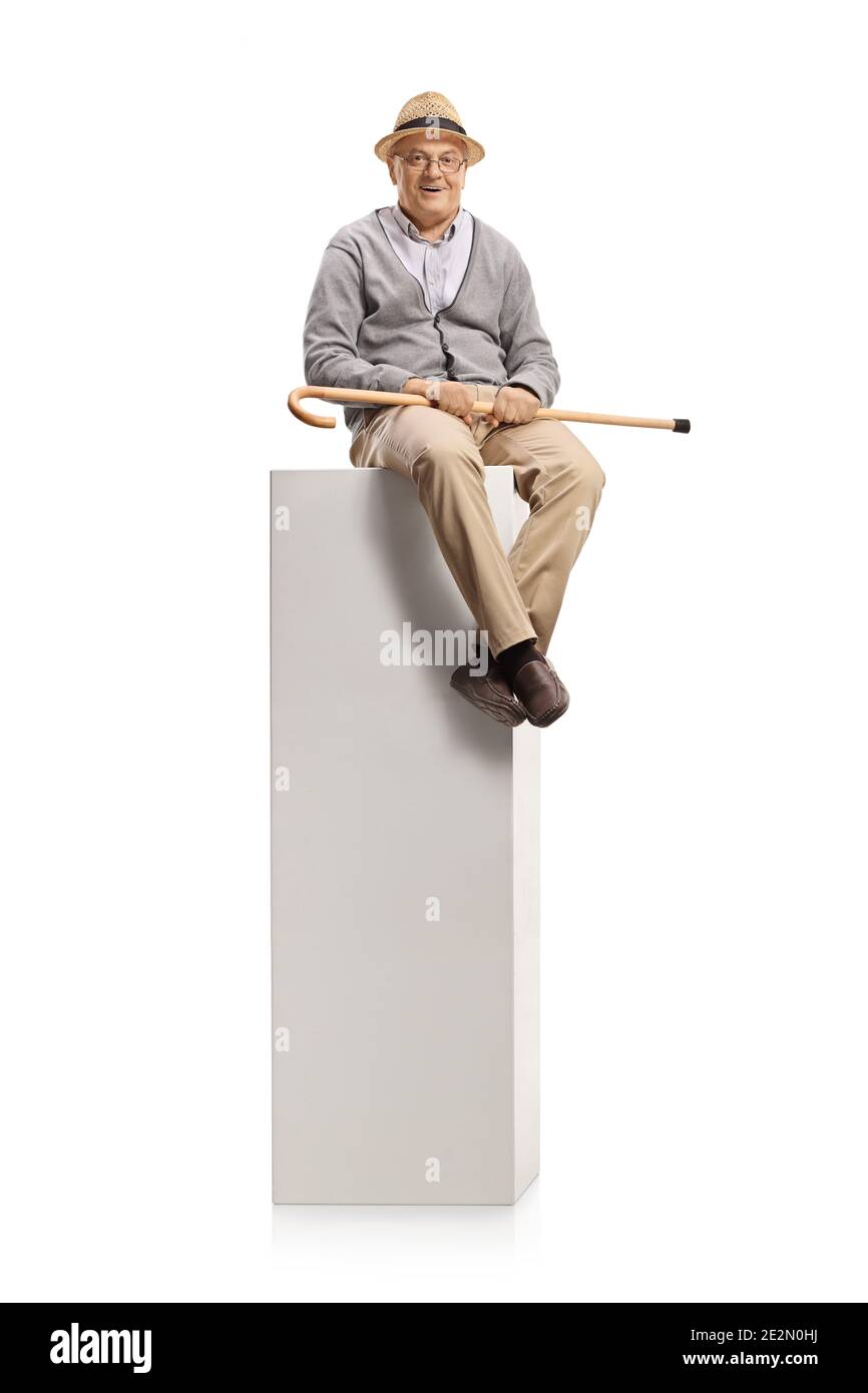 Homme âgé assis sur une colonne et tenant une marche canne isolée sur fond blanc Banque D'Images