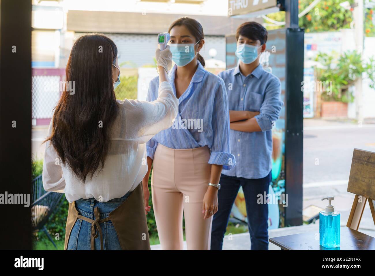 Femme asiatique employé de café prendre la température femme asiatique avec le visage masque avant d'aller au restaurant ou au café pour nouveau coronavirus cov de style de vie normal Banque D'Images