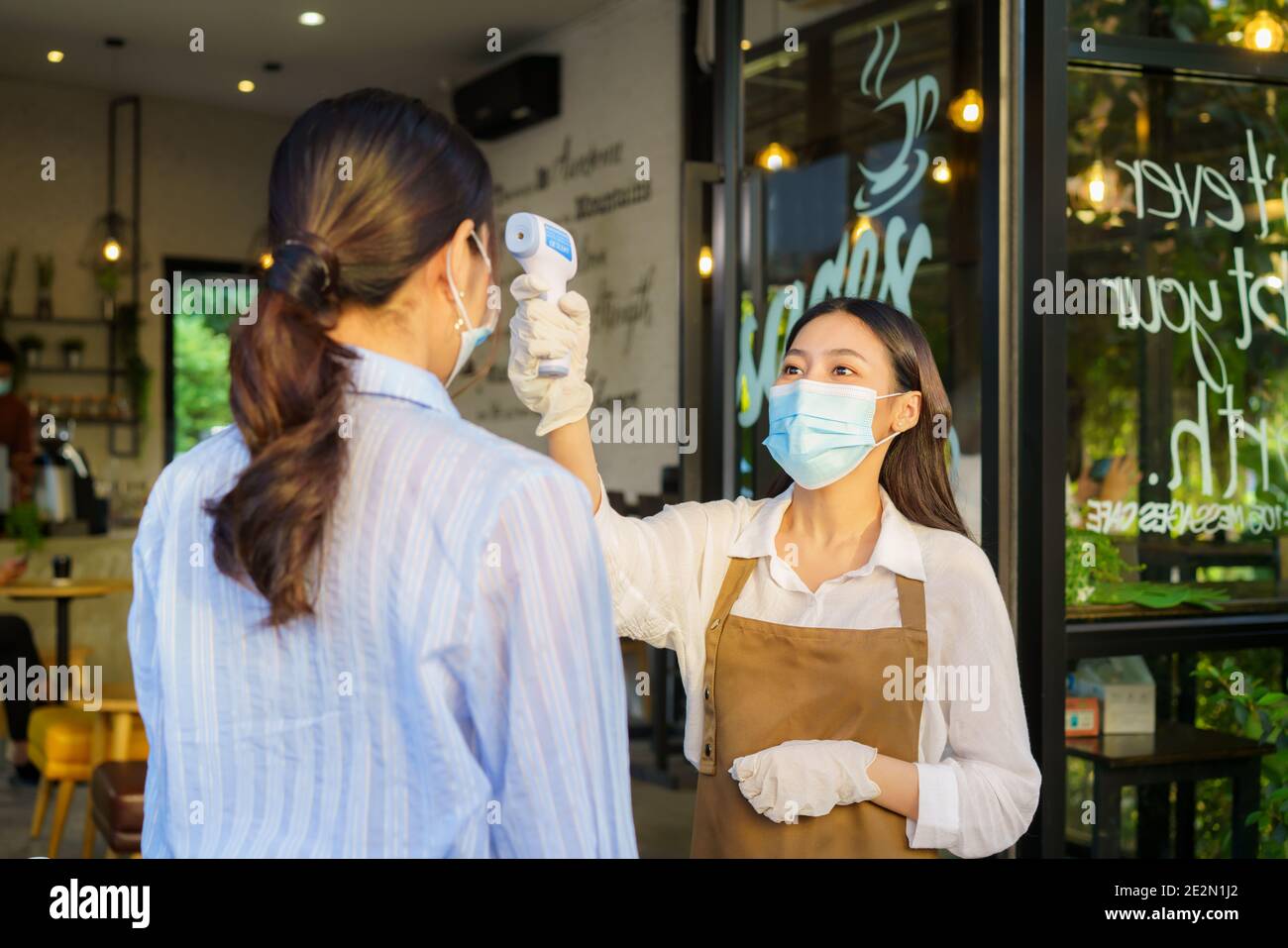 Femme asiatique employé de café prendre la température femme asiatique avec le visage masque avant d'aller au restaurant ou au café pour nouveau coronavirus cov de style de vie normal Banque D'Images