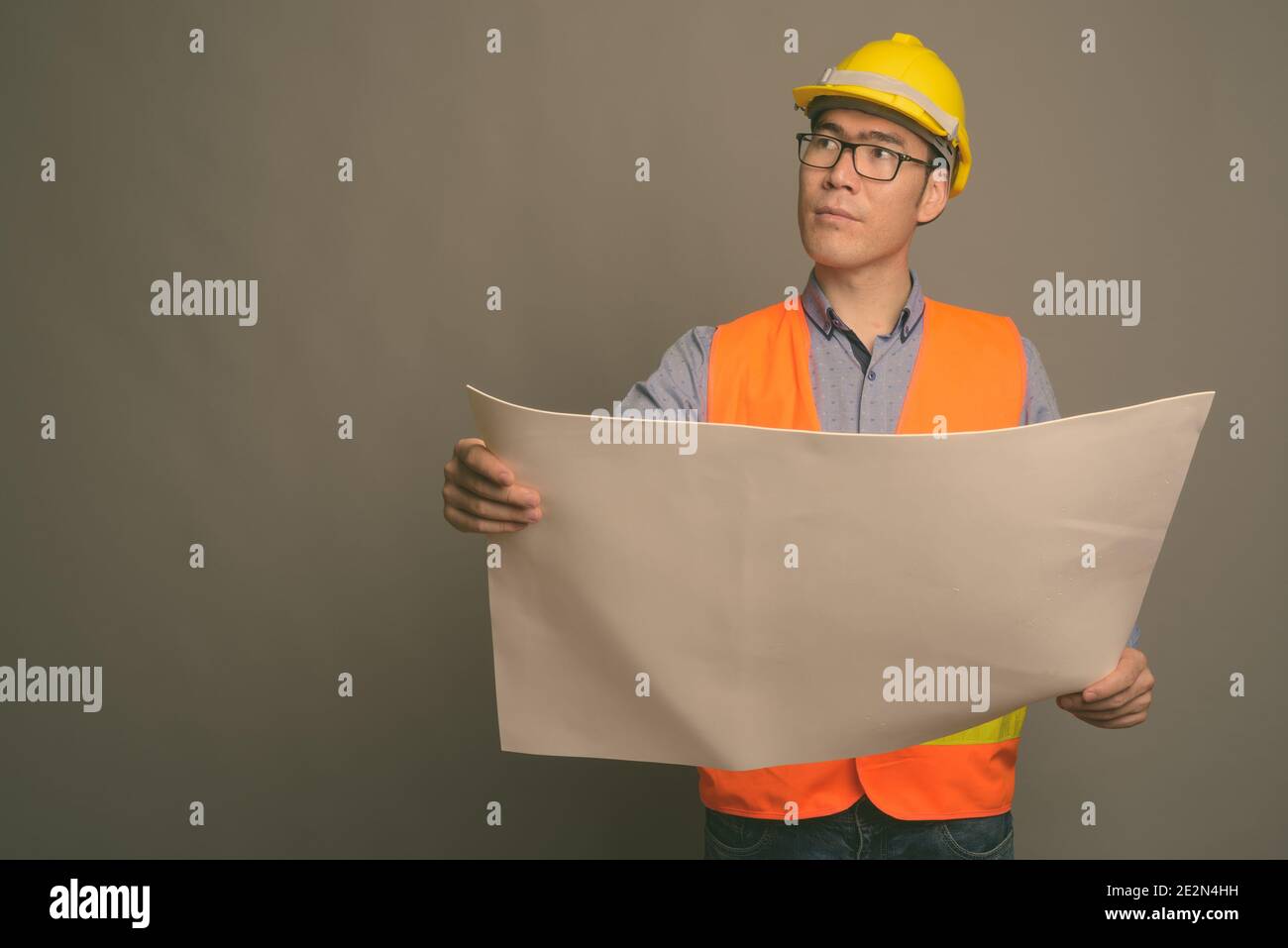 Young Asian man construction worker contre l'arrière-plan gris Banque D'Images