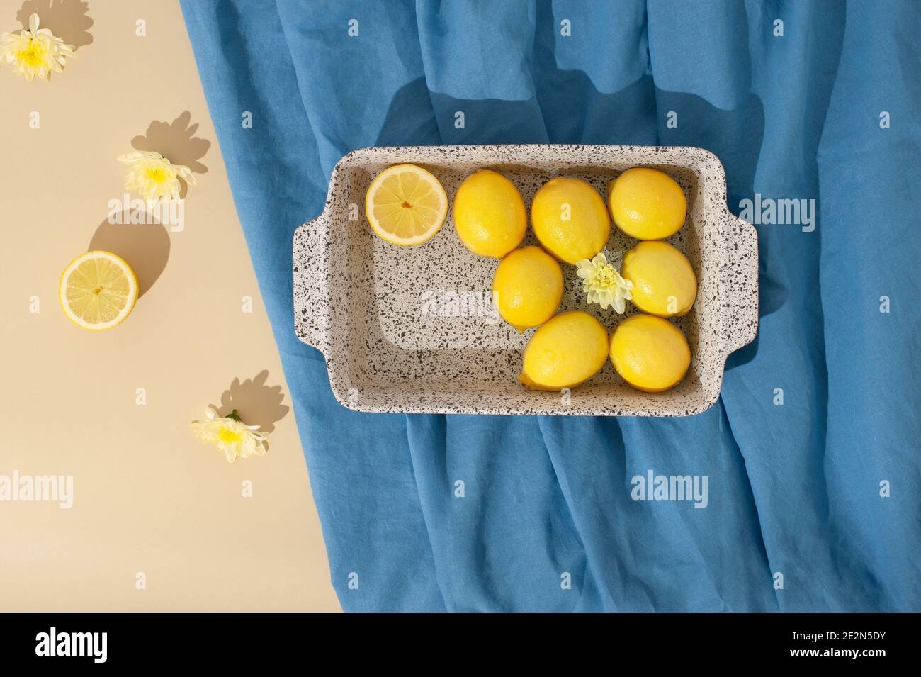 Scène estivale avec citrons, fleurs jaunes et serviette de plage bleue sur fond beige pastel. Flat lay.arrière-plan abstrait minimal. Banque D'Images