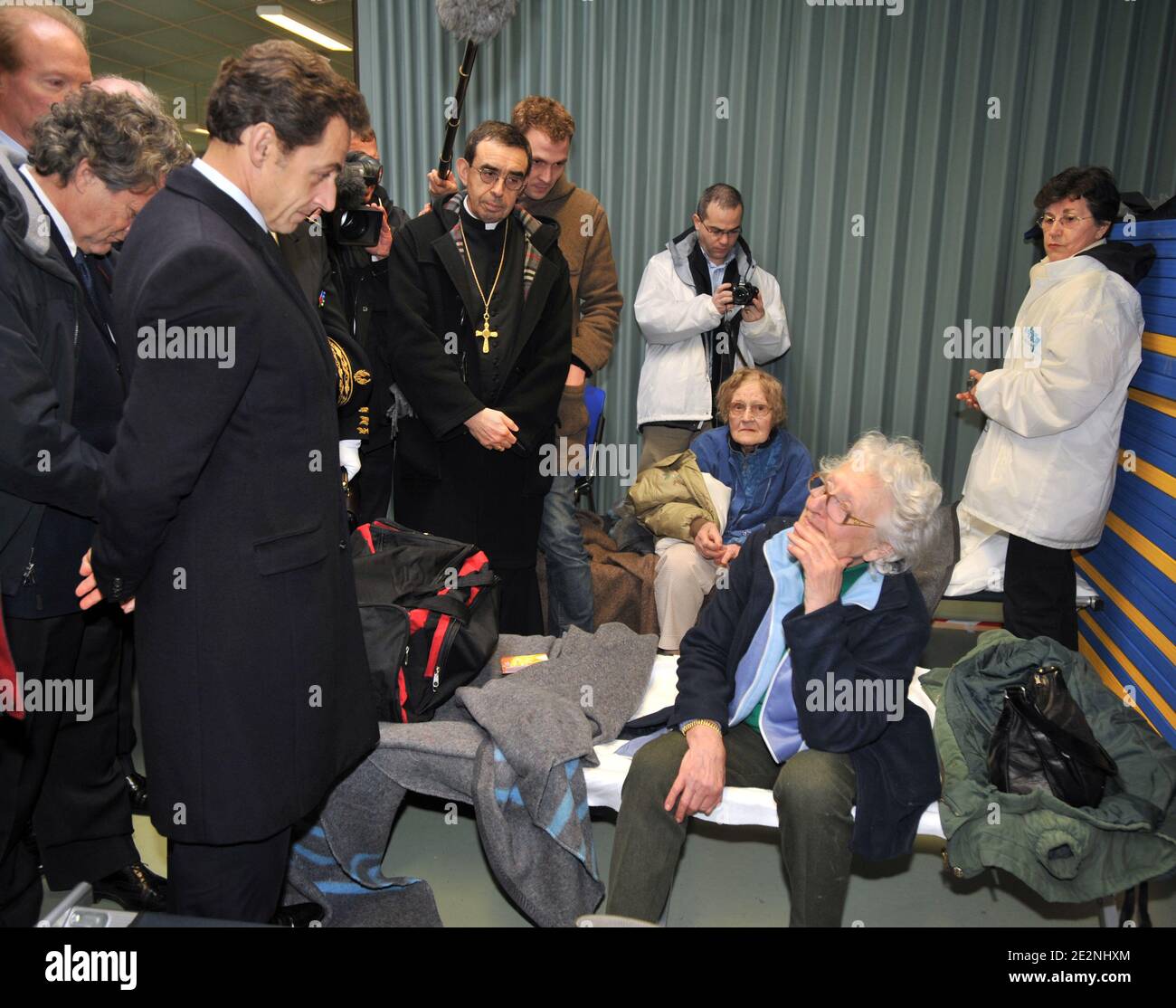 Le président français Nicolas Sarkozy (2ndL), flanqué de la ministre de l'intérieur Brice Hortefeux (L) et du ministre de l'écologie Jean-Louis Borloo (2ndL, partiellement caché), écoute une victime de la tempête Xynthia, abritée dans une école de l'Aiguillon-sur-Mer, dans l'ouest de la France, le 1er mars, 2010 après avoir survolé les zones inondées entre la Rochelle et l'Aiguillon-sur-Mer. Xynthia a frappé cette partie de la côte atlantique la veille, tuant au moins 50 personnes, faisant des vagues énormes dans les villes exposées, inondant des centaines de maisons. Bussereau est président du conseil général de la Charente-Maritime, près de Vendée Banque D'Images