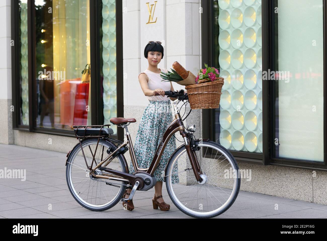 femme avec vélo électrique et sacs de shopping dans la ville Banque D'Images