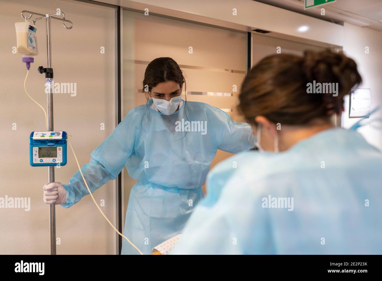 deux infirmières aident un patient à marcher dans un couloir Banque D'Images