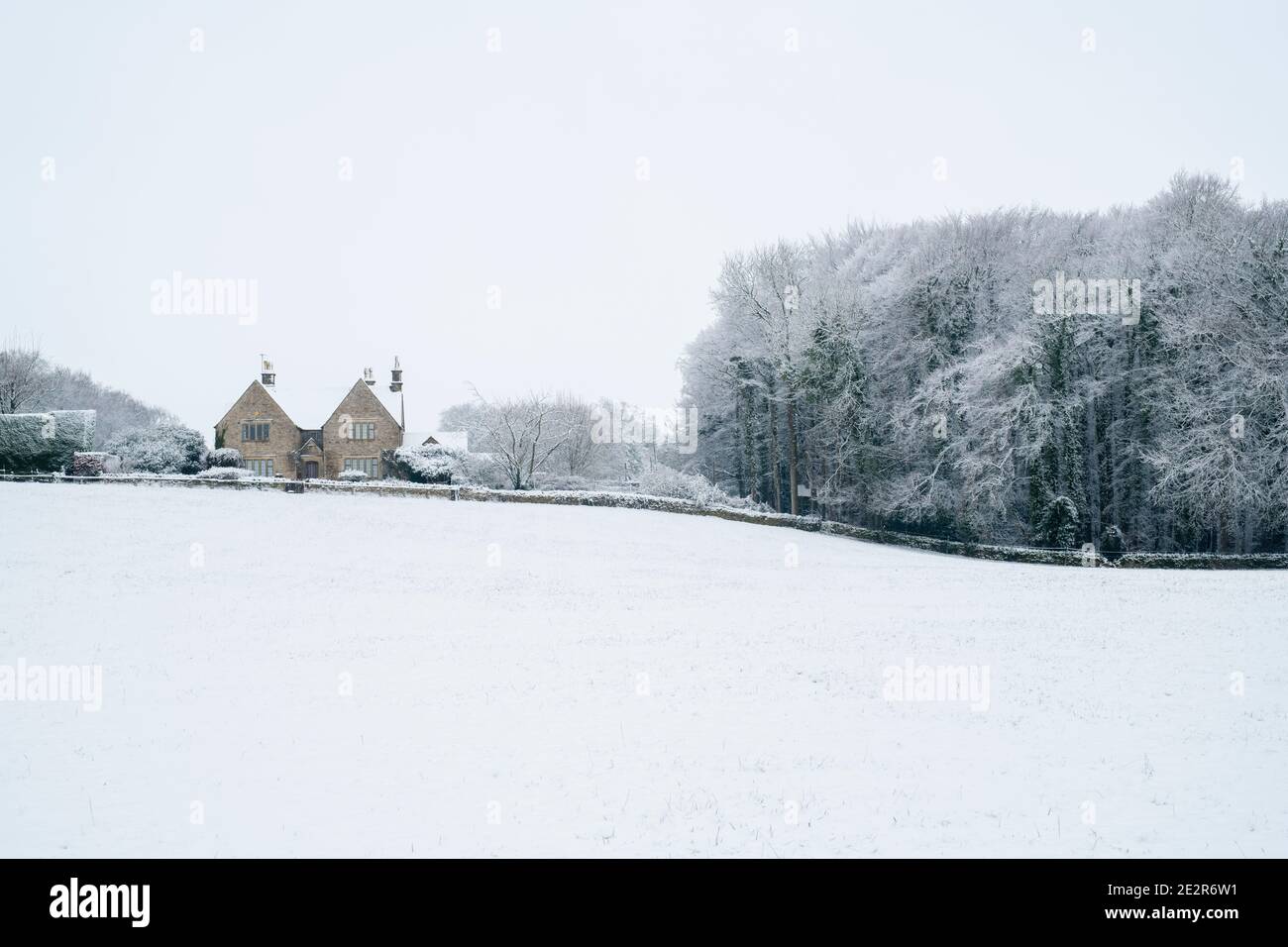 Maison en pierre de Cotswold, arbres et champ dans la neige de décembre dans la campagne de cotswold. Près de Upper Slaughter, Cotswolds, Gloucestershire, Angleterre Banque D'Images