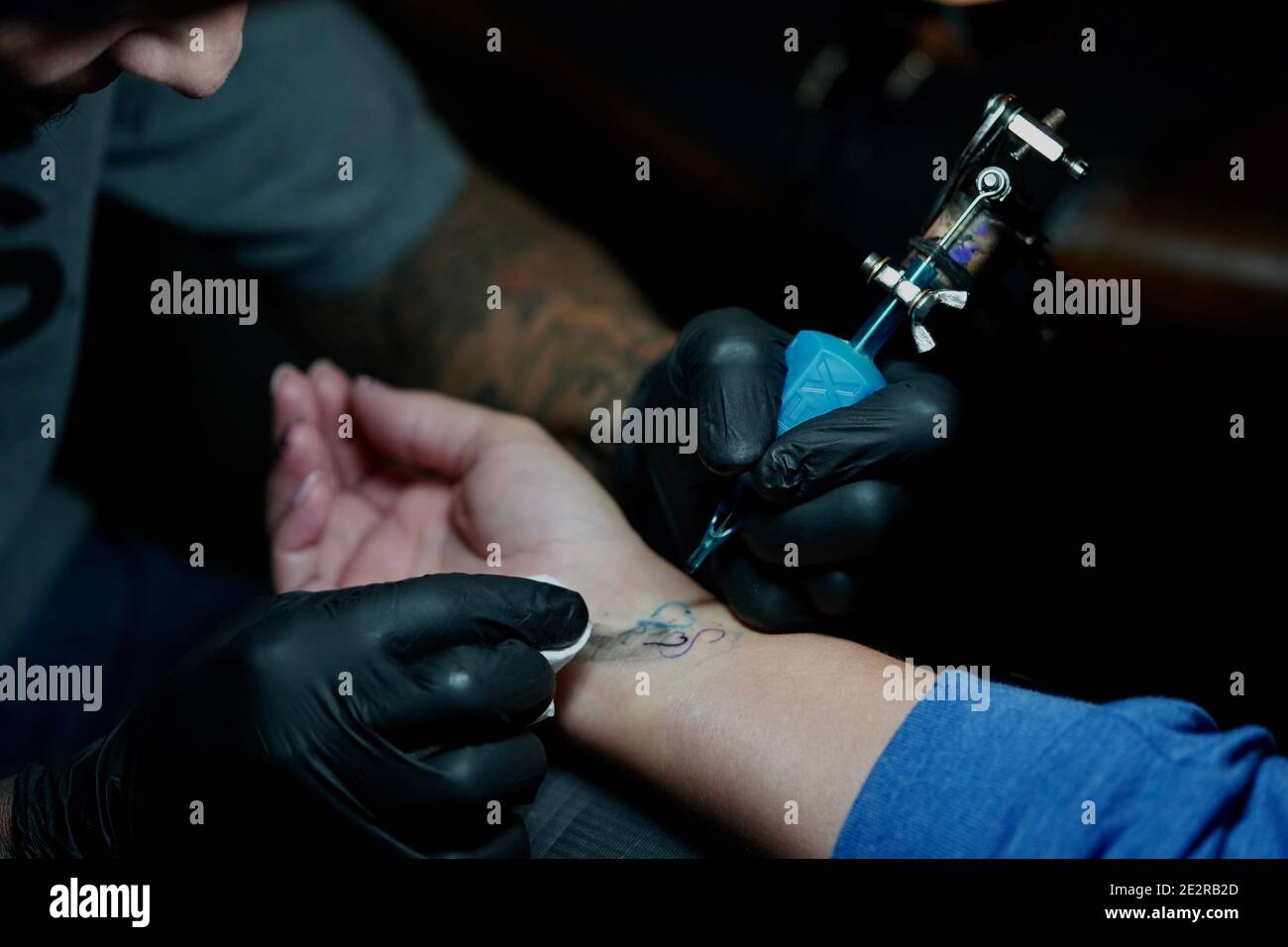 Une vue rapprochée d'une femme obtenant la lettre "s" avec un coeur tatoué à l'intérieur de son poignet. Banque D'Images