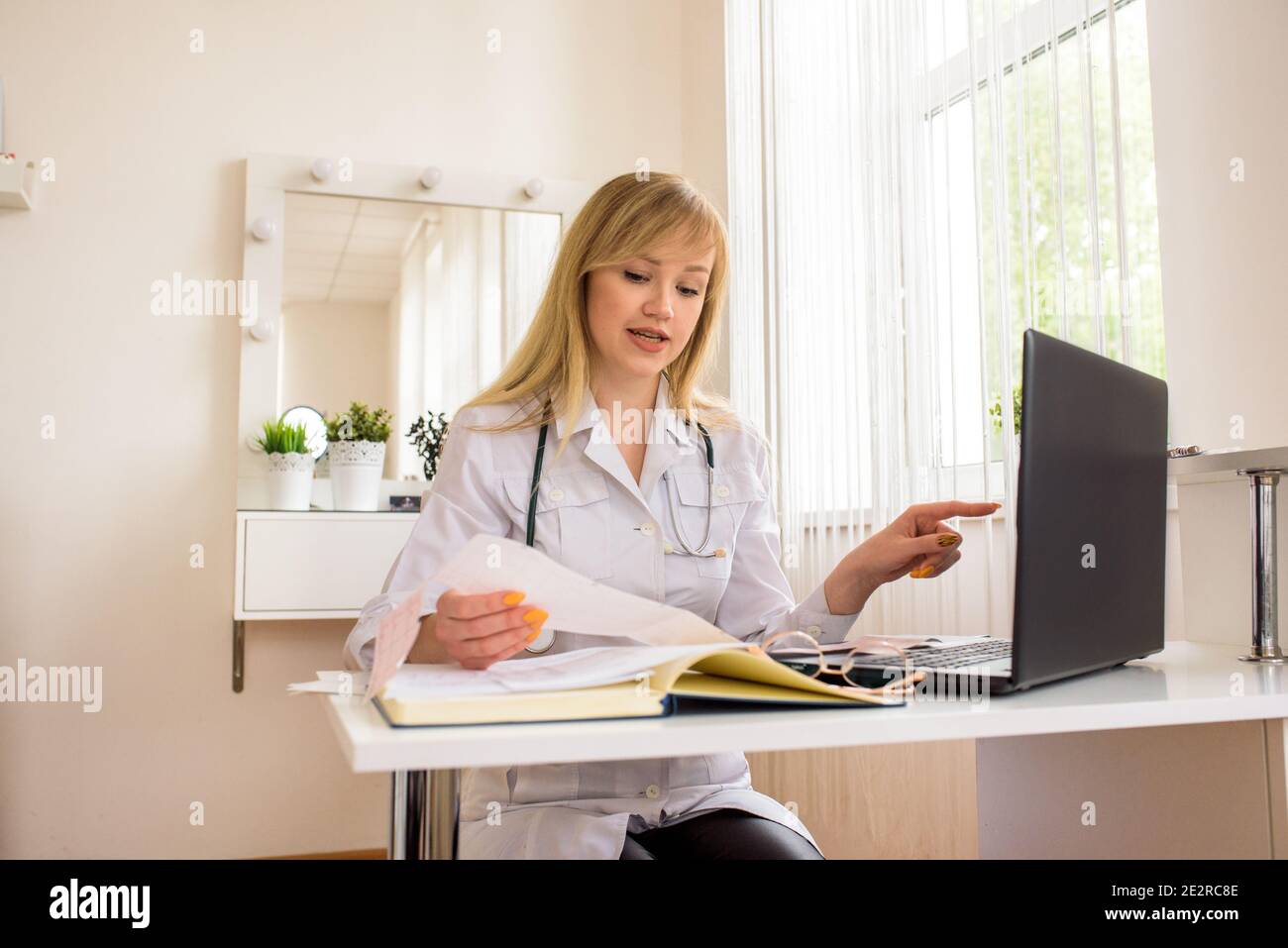 Consultation de médecin en ligne au bureau. Jeune médecin travaillant sur un ordinateur portable. Parle et traite la distance. Conversation avec un web patient. Banque D'Images