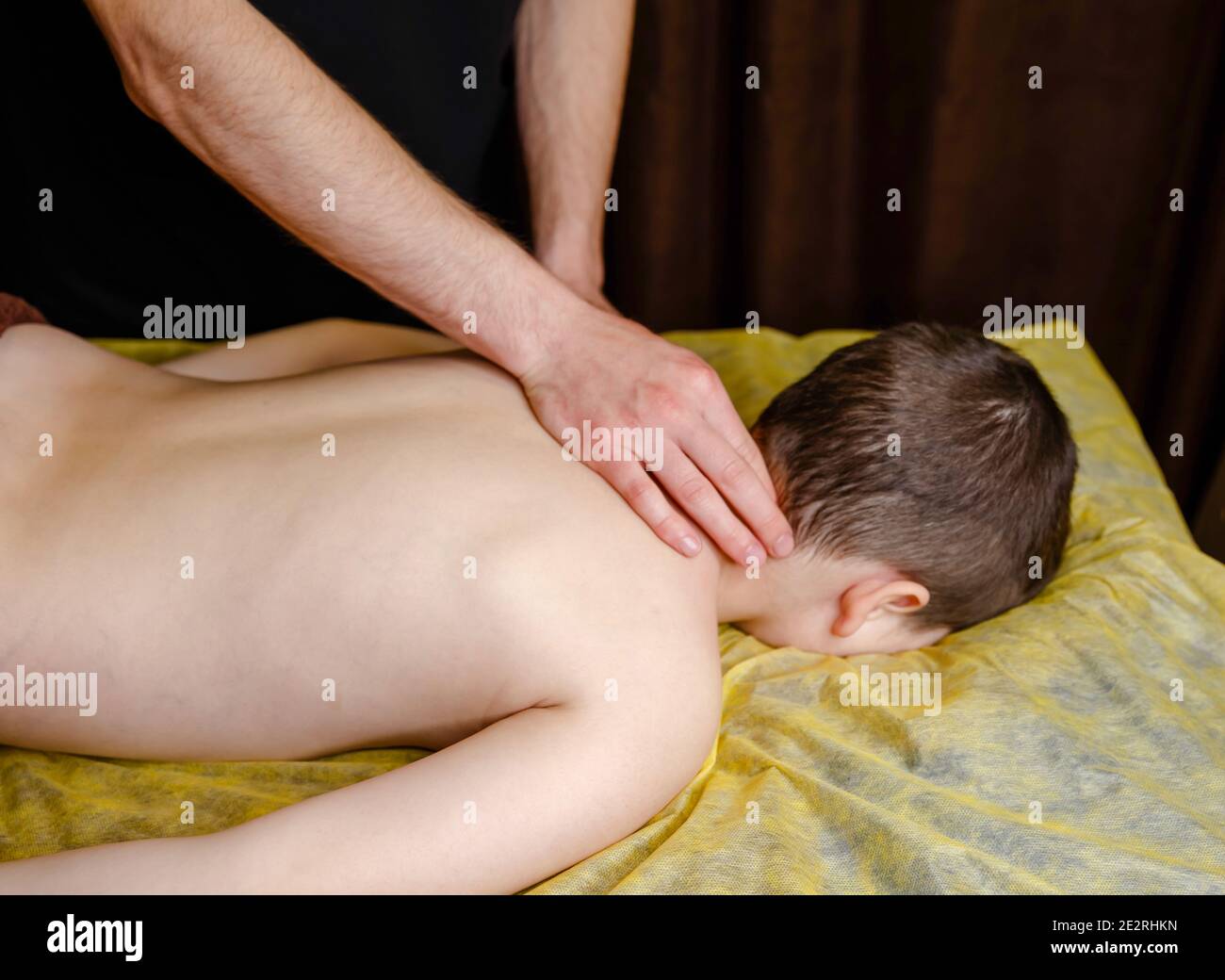 Le tout-petit se détend d'un massage thérapeutique. Les mains d'un masseur Banque D'Images