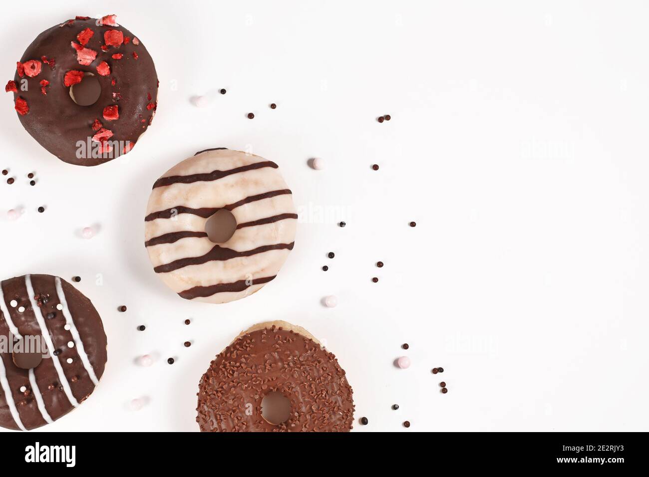 Beignets avec glaçage au chocolat et saupoudrer dans un coin de blanc arrière-plan avec espace de copie vide Banque D'Images