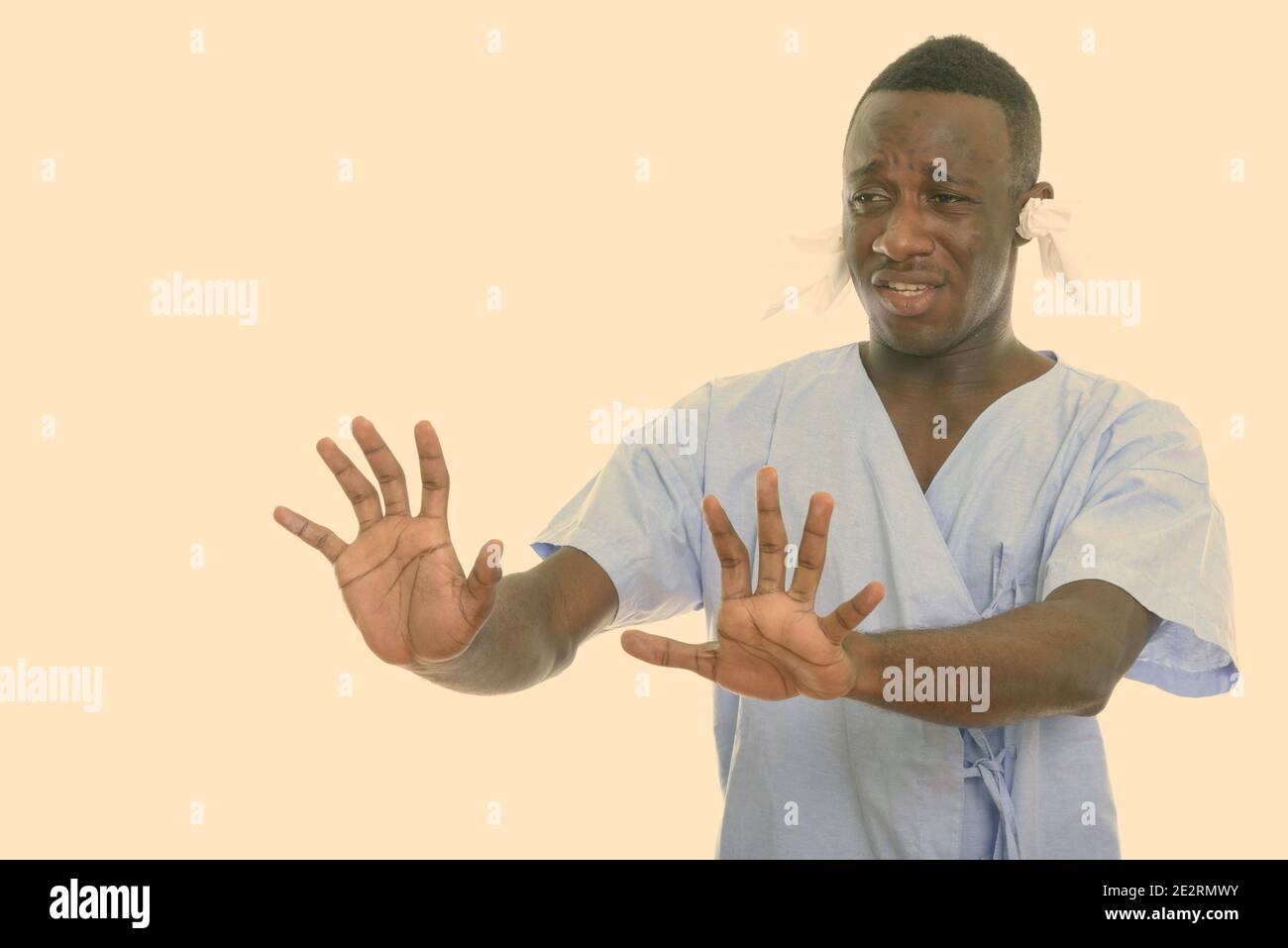 Portrait de jeune homme de l'Afrique noire à la recherche de patients malades avec des tissus dans ses oreilles et montrant un panneau d'arrêt avec les deux mains Banque D'Images