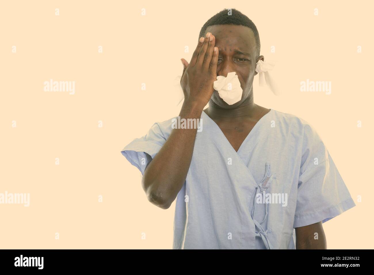 Studio shot of young black African man patient ayant des maux de tête et à la malade de tissus dans ses oreilles et nez Banque D'Images