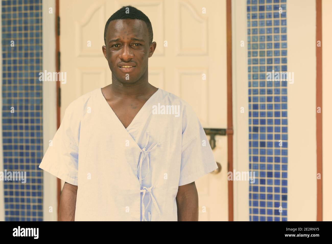 Studio shot of young black African man patient dans la porte d'entrée à la maison Banque D'Images