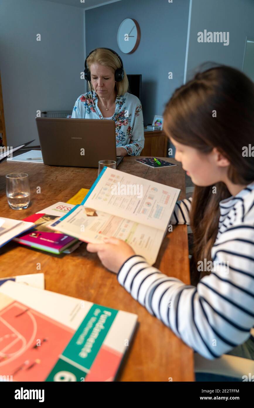 Homeschooling, pendant le verrouillage de janvier 2021, les enfants étudiant à la maison pour l'école, leur mère dans le bureau à domicile travaillant sur l'ordinateur portable avec vide Banque D'Images