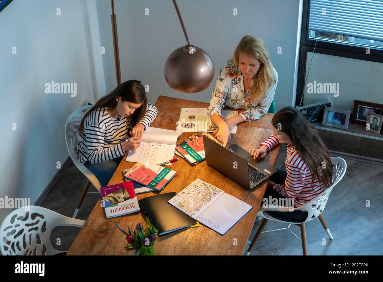 Homeschooling, pendant le confinement en janvier 2021, la mère aide ses deux filles, à la maison, à apprendre, avec des manuels et des ordinateurs, des fermetures d'écoles, Banque D'Images