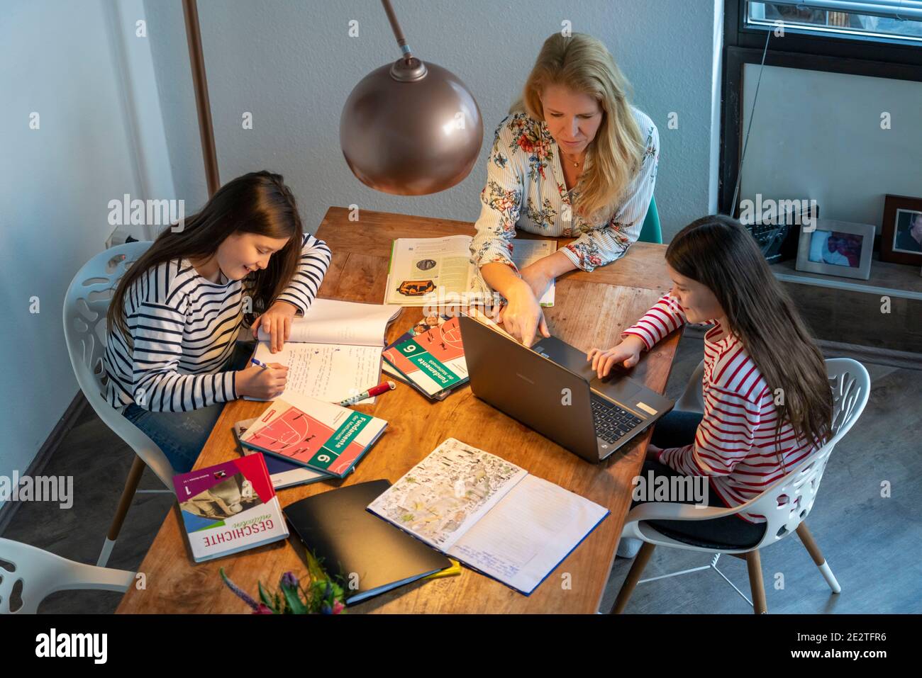 Homeschooling, pendant le confinement en janvier 2021, la mère aide ses deux filles, à la maison, à apprendre, avec des manuels et des ordinateurs, des fermetures d'écoles, Banque D'Images