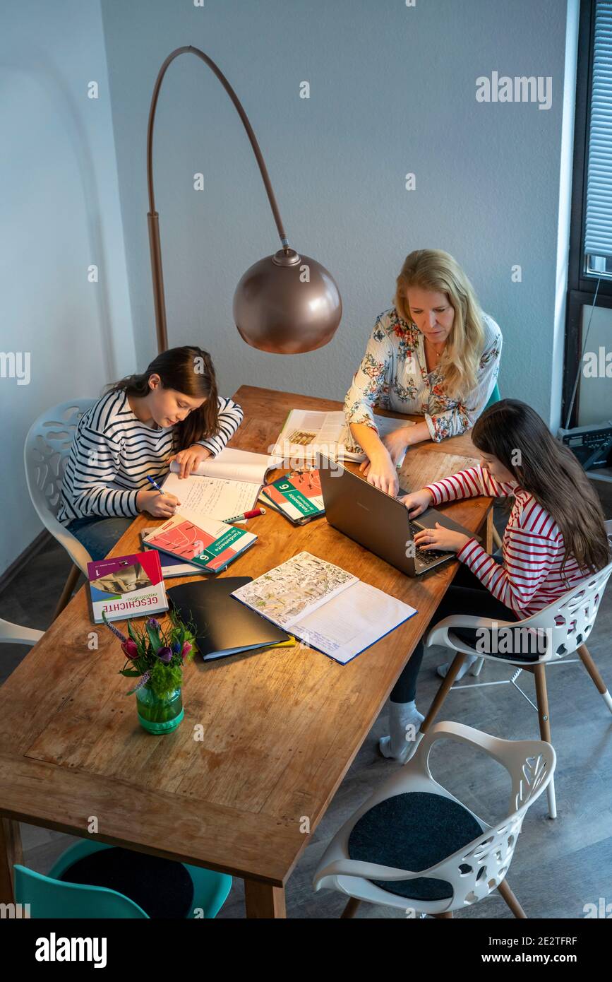 Homeschooling, pendant le confinement en janvier 2021, la mère aide ses deux filles, à la maison, à apprendre, avec des manuels et des ordinateurs, des fermetures d'écoles, Banque D'Images