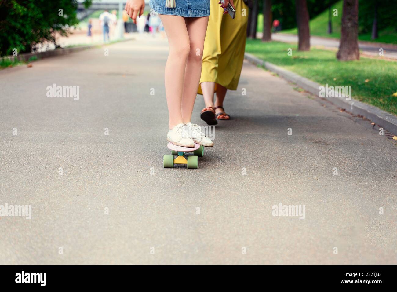 une fille de peinture blanche monte un panneau de penny. Image de style de vie en plein air lors d'une journée ensoleillée d'été. Banque D'Images