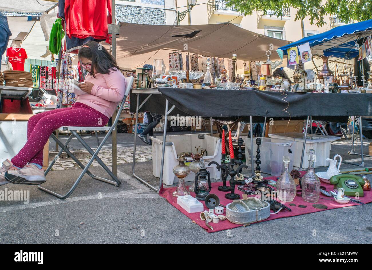 Jeune fille lisant, stand bric-a-brac au Mercado de Santa Clara (Feira da Ladra), marché aux puces à la place Campo de Santa Clara à Lisbonne, Portugal Banque D'Images