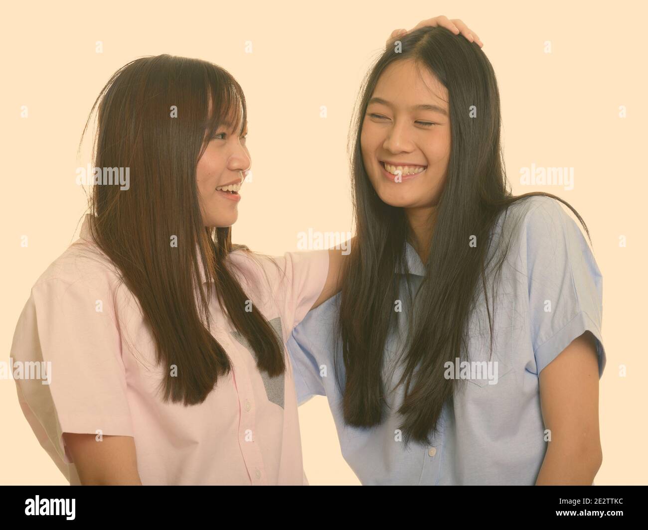 Deux jeunes professionnels Asian teenage girls smiling et tapotant son ami sur la tête Banque D'Images