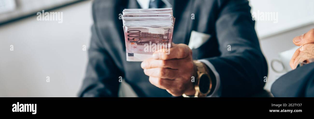 Vue rognée de l'investisseur détenant des billets en euros près de l'homme d'affaires sur un premier plan flou, bannière Banque D'Images