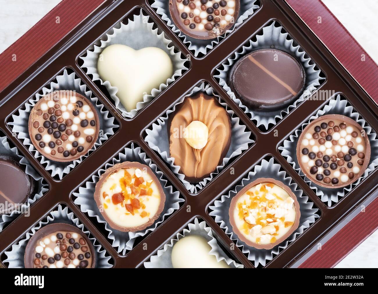 Différentes pralines au chocolat. Boîte de pralines belges de différentes formes. Assortiment de chocolats fins belges blancs, noirs et au lait Banque D'Images