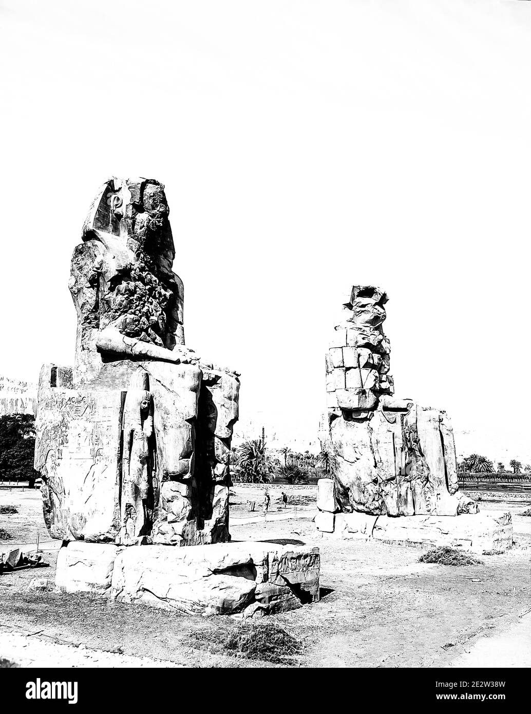 Louxor. C'est le site archéologique 1350BC au Colossi de Memnon de l'Égypte ancienne, non loin du Nil et de la ville de Louxor connu auparavant sous le nom de Thèbes. Les statues sont du Pharaon Amenhotep III, il y a deux petites statues à ses pieds, l'une étant sa mère, l'autre son épouse. Initialement construit pour protéger l'entrée du temple d'Amenotep contre le mal, ils ont également été vus pour protéger la rive ouest du Nil. Les Colossi ont subi des dommages importants après le tremblement de terre, mais après 3500 ans, ils restent debout. Banque D'Images