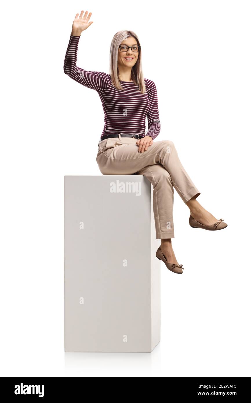 Jeune femme professionnelle assise sur une colonne blanche et agitant isolé sur fond blanc Banque D'Images