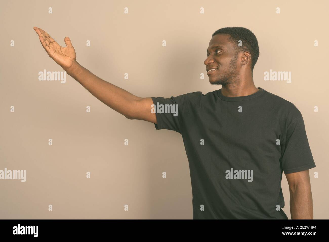 Jeune homme africain portant chemise noire contre l'arrière-plan gris Banque D'Images