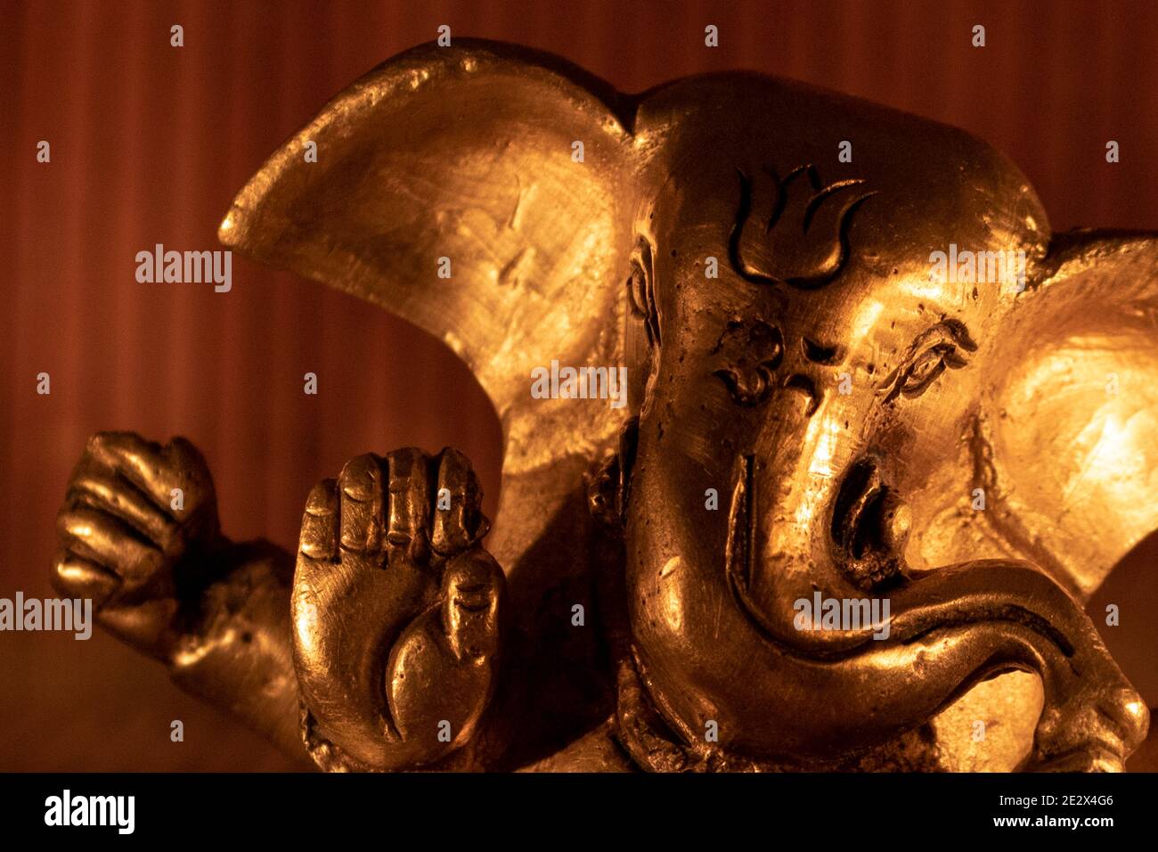 Gros plan d'une statue Golden Lord Ganesha avec éclairage ambiant chaud Banque D'Images
