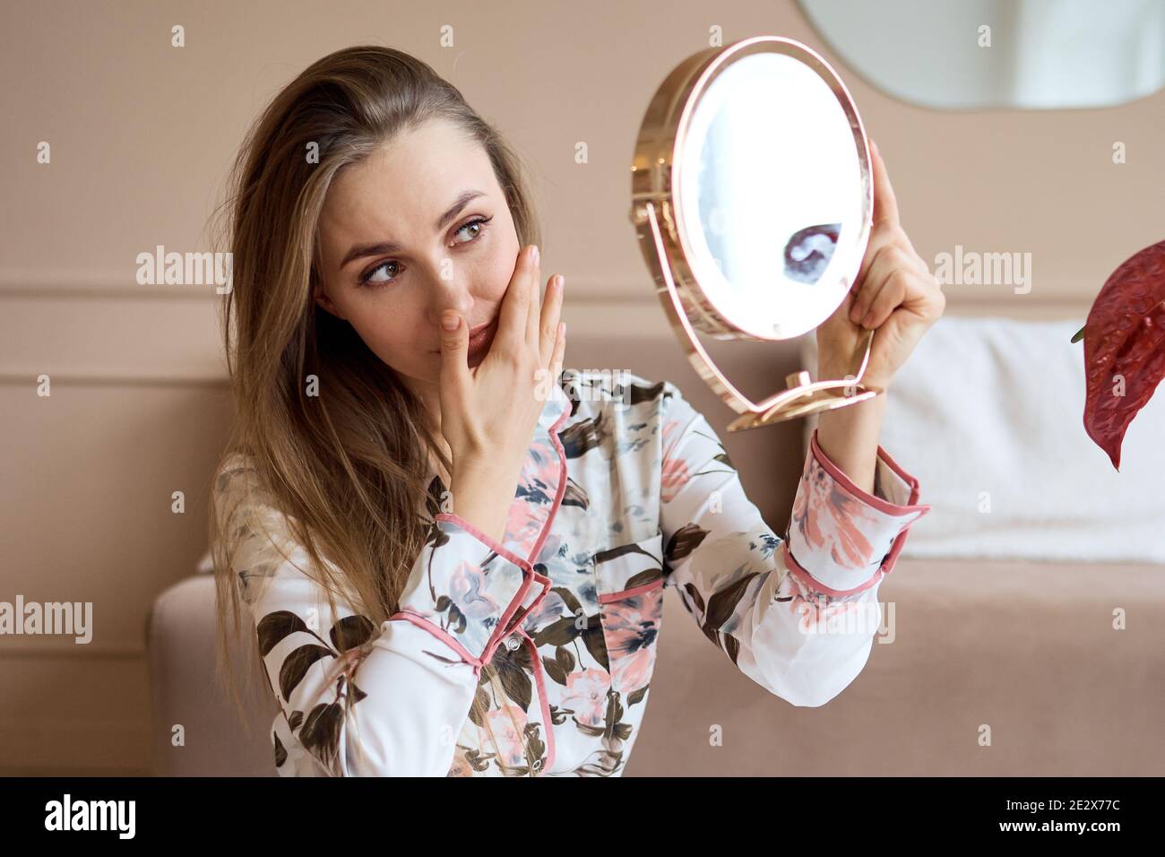 Belle femme en pyjama appliquant la crème du visage. Belle jeune femme en pyjama appliquant de la crème hydratante sur le visage. Frais du matin Banque D'Images