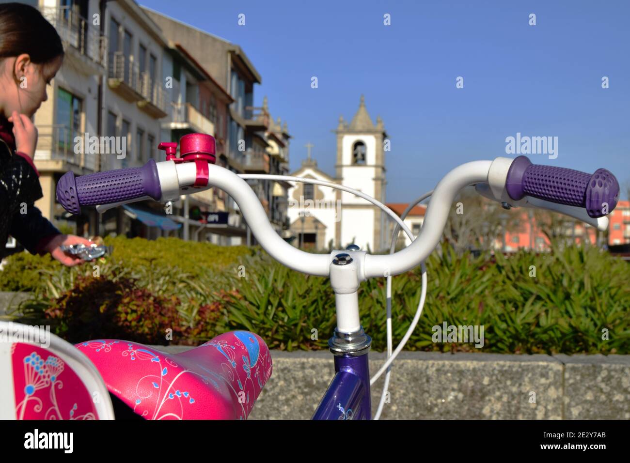 Petite fille près de son premier vélo avec une église sur le fond, grandissant des temps et apprendre à monter un vélo Banque D'Images