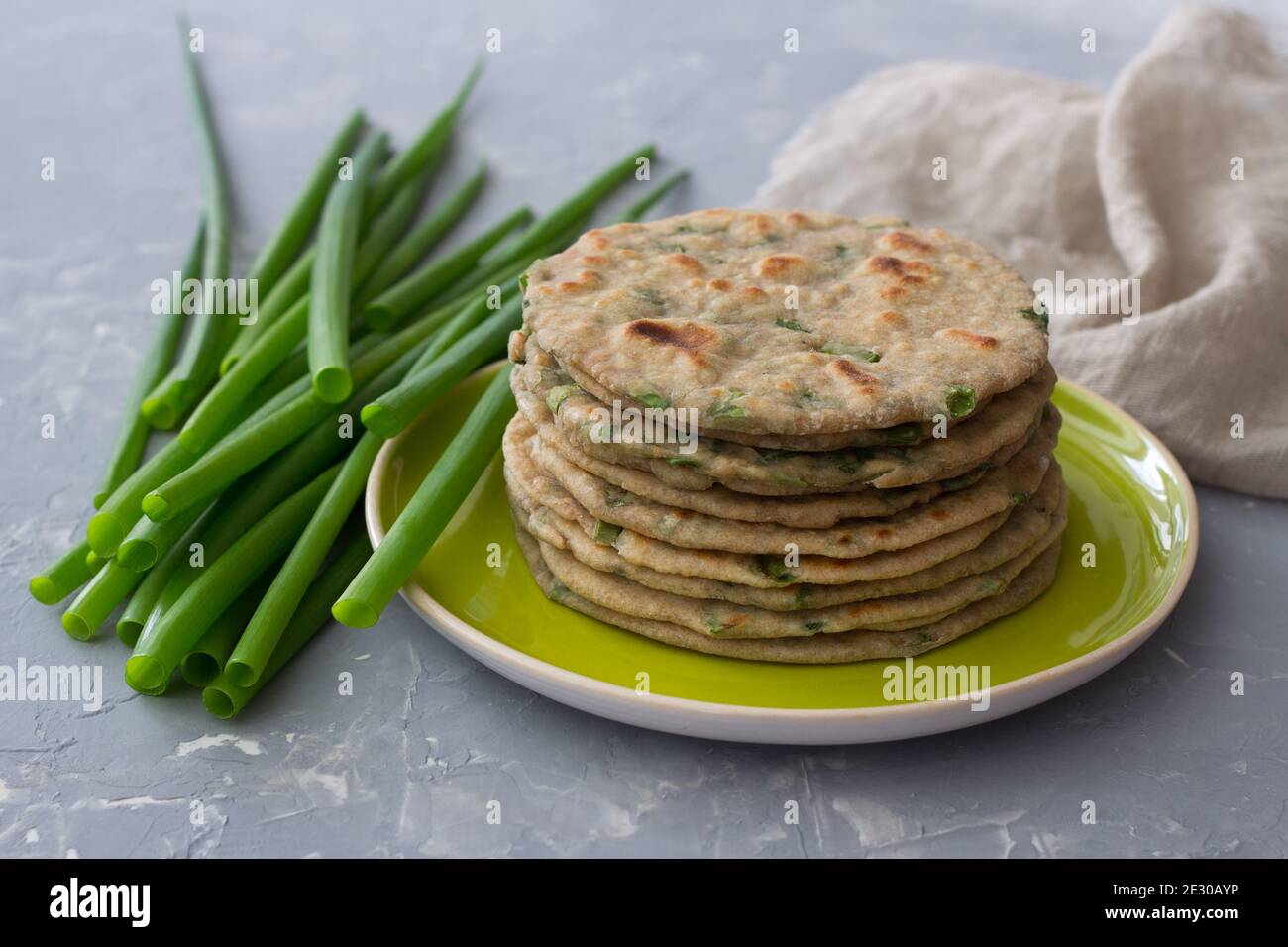 Pain plat complet de seigle de blé avec oignons verts sur fond gris. Aliments sains faits maison Banque D'Images