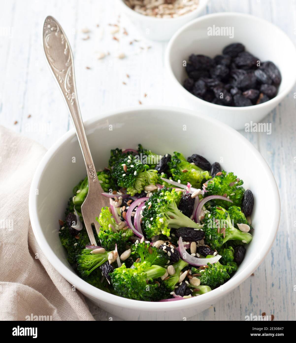Salade fraîche au brocoli, raisins noirs, oignons rouges, graines, sésame et lin sur fond léger. Alimentation saine. Sélection Banque D'Images