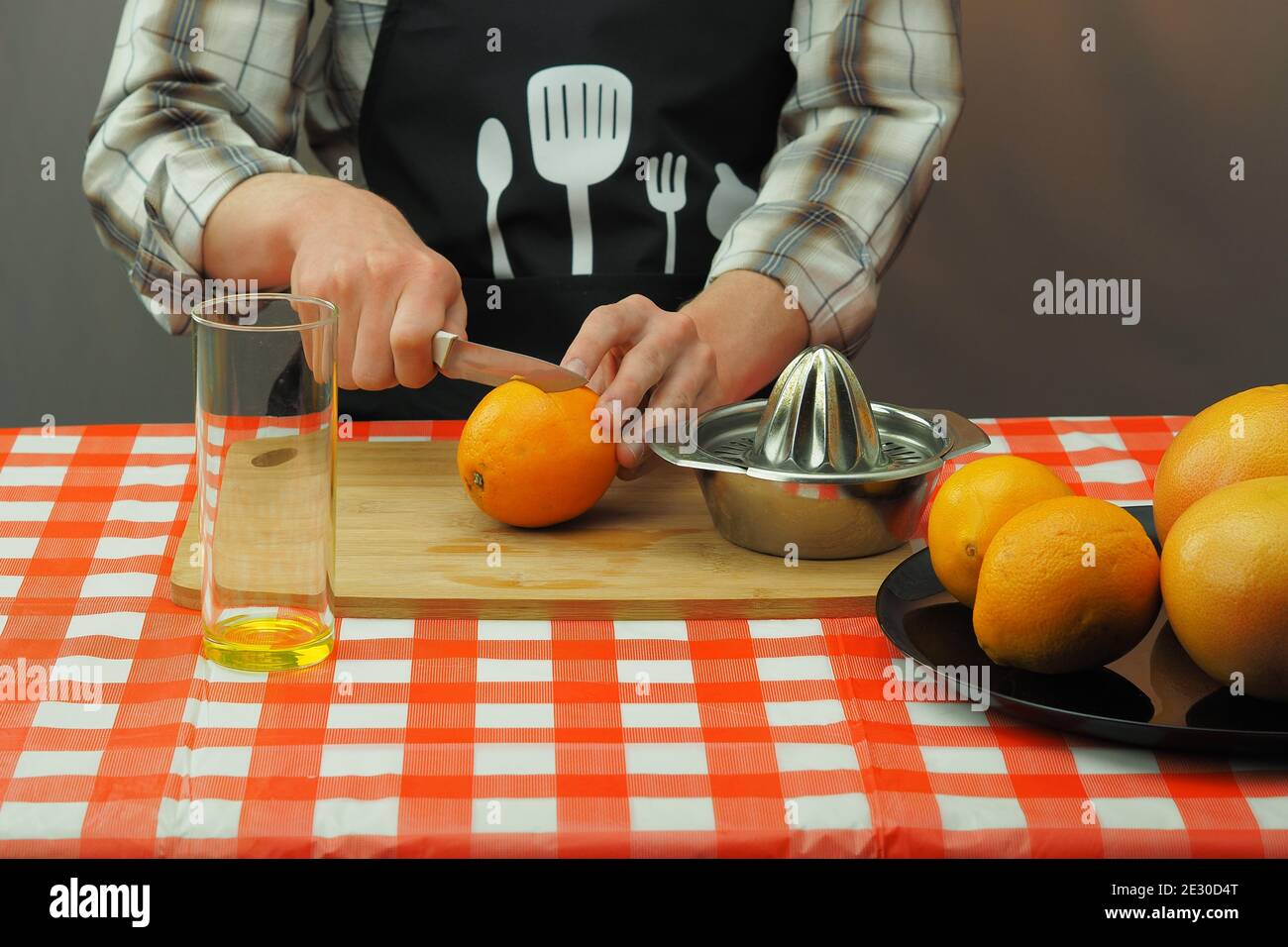 Un jeune homme en tablier prépare du jus fraîchement pressé à partir  d'orange et de pamplemousse Photo Stock - Alamy
