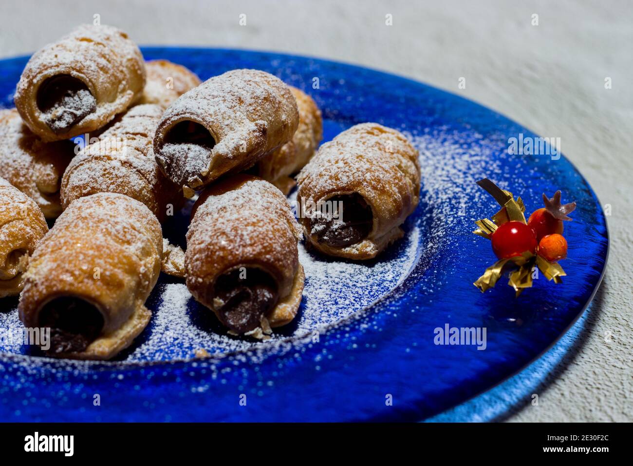 Cannoli au chocolat. Bonbons au chocolat italien sur une assiette bleue et un fond blanc. Banque D'Images