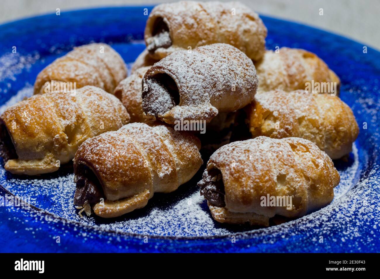 Cannoli au chocolat. Bonbons au chocolat italien sur une assiette bleue et un fond blanc. Banque D'Images