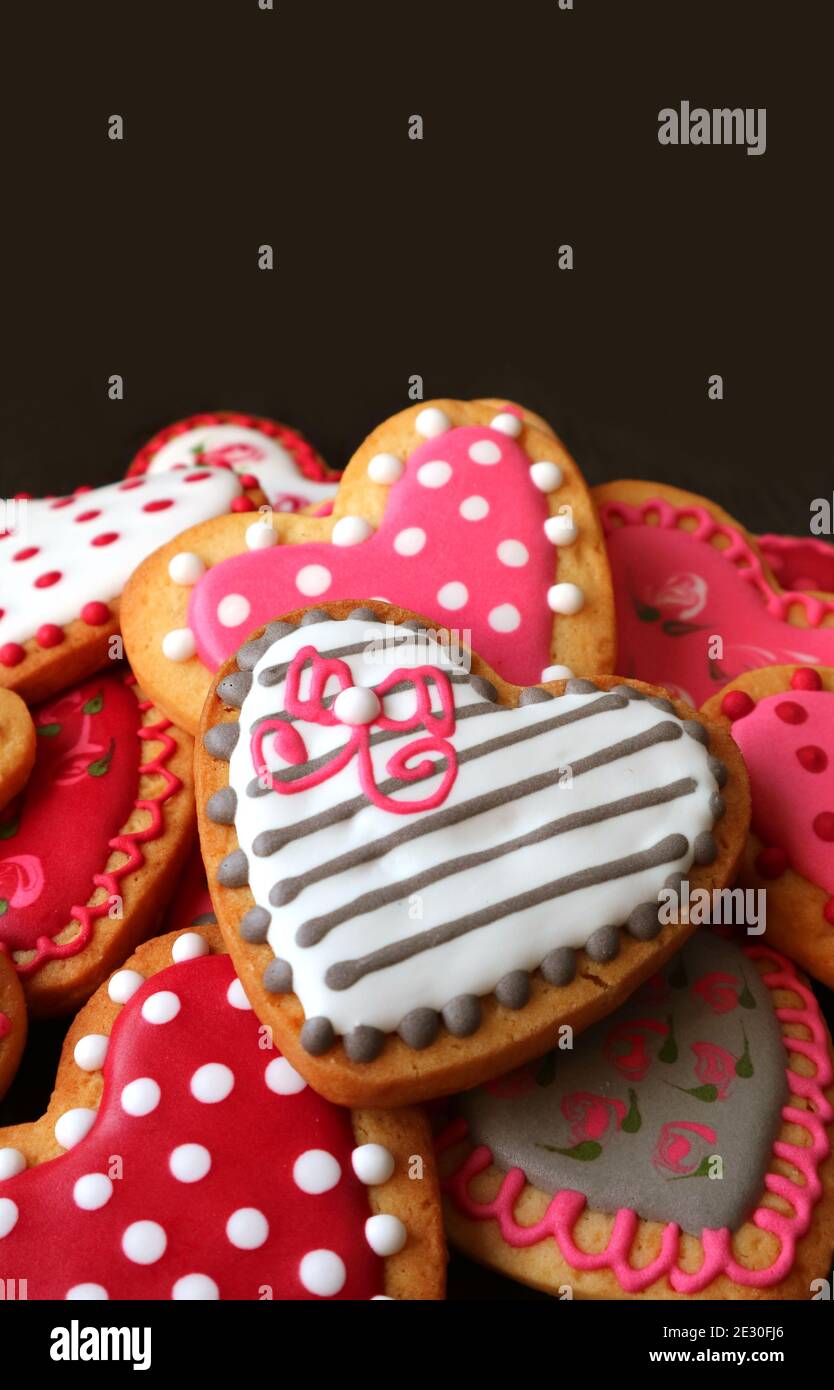 Tas de coeur en forme avec de jolis biscuits sur le noir arrière-plan Banque D'Images