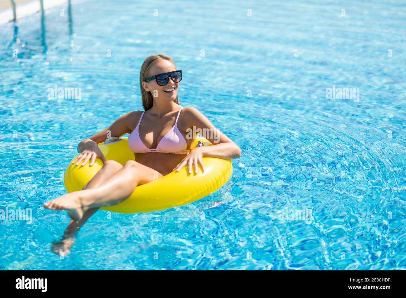 Happy young woman in bikini avec flotteur gonflable en caoutchouc, de jouer et d'avoir un bon temps au parc aquatique piscine, sur une chaude journée d'été Banque D'Images