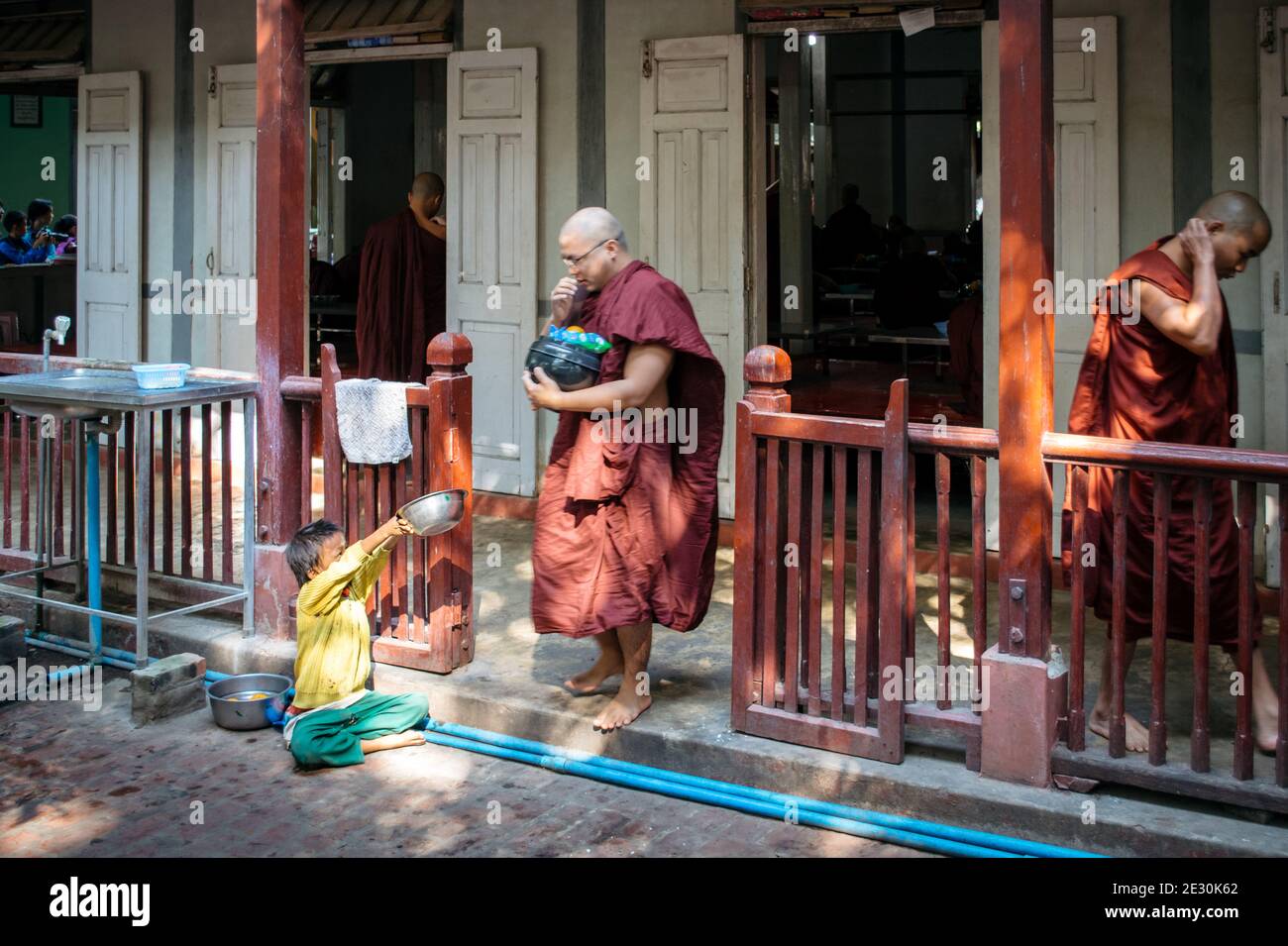 Amarapura, Myanmar - le gamin supplie de manger aux moines bouddhistes du monastère de Mahagandhayon. Banque D'Images