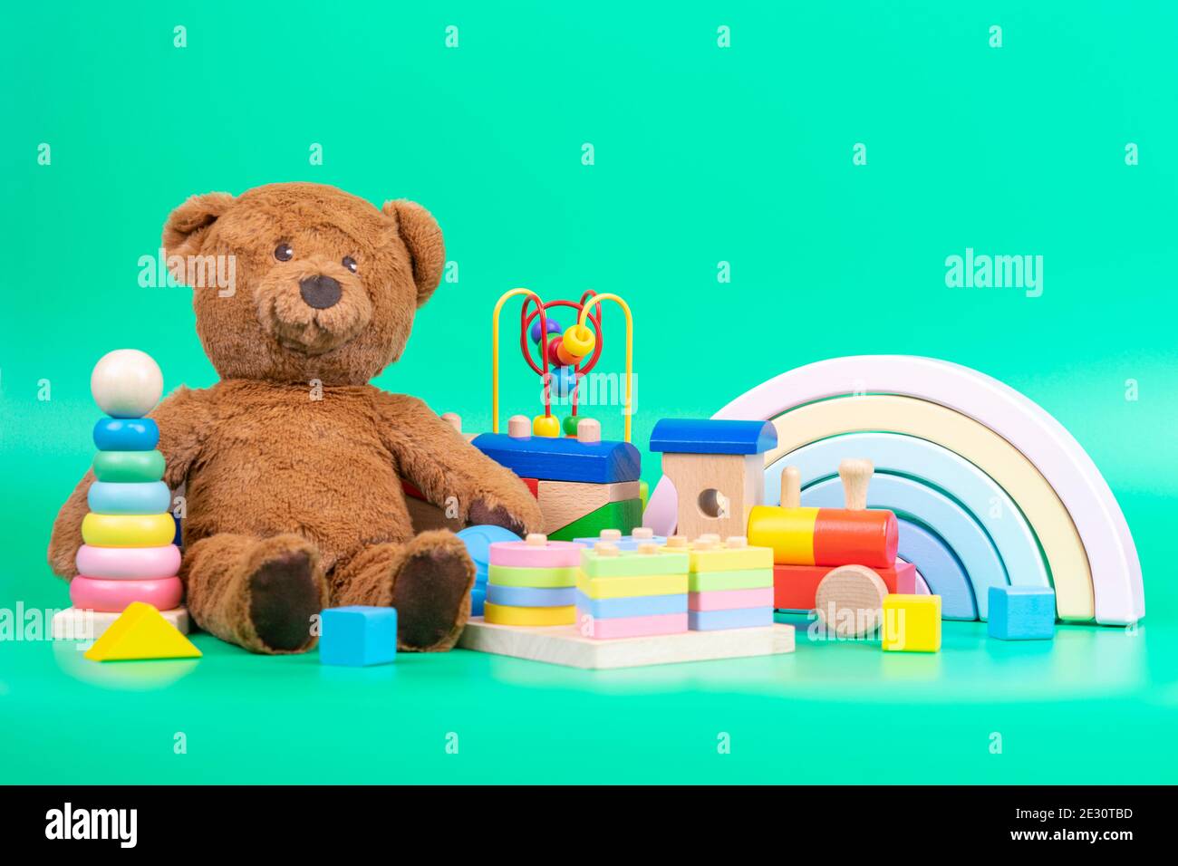 Collection de jouets pour enfants. Ours en peluche, arc-en-ciel en bois,  train et jouets pour bébés sur fond vert clair Photo Stock - Alamy