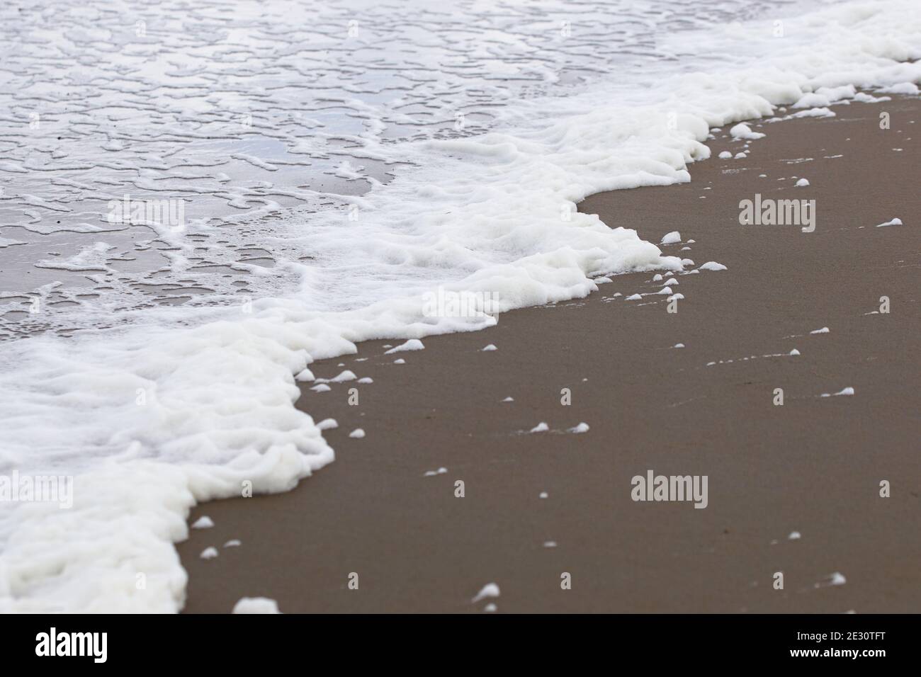 gros plan de la ligne de mer avec de la mousse, de l'eau mousseuse à la plage de sable noir Banque D'Images