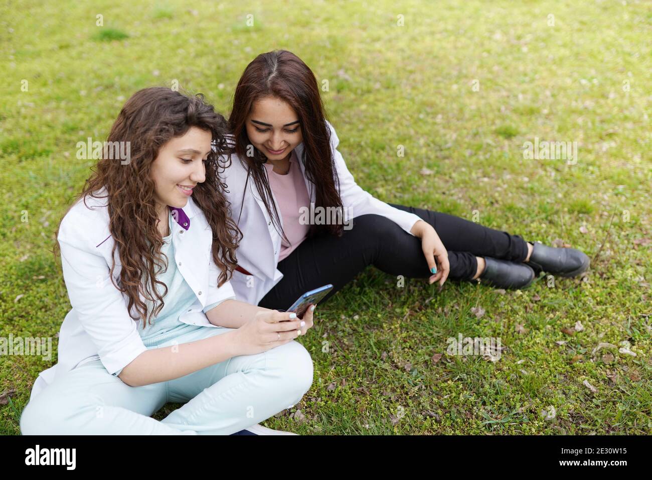 femmes médecins étudiant à l'extérieur avec téléphone . milieu médical . étudiants près de l'hôpital dans le jardin de fleurs Banque D'Images