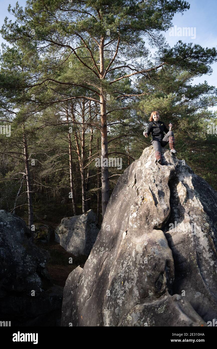 Une femme grimpeur se délectant à l'extérieur sous le soleil sur le Rochers de grès de Fontainebleau en France Banque D'Images