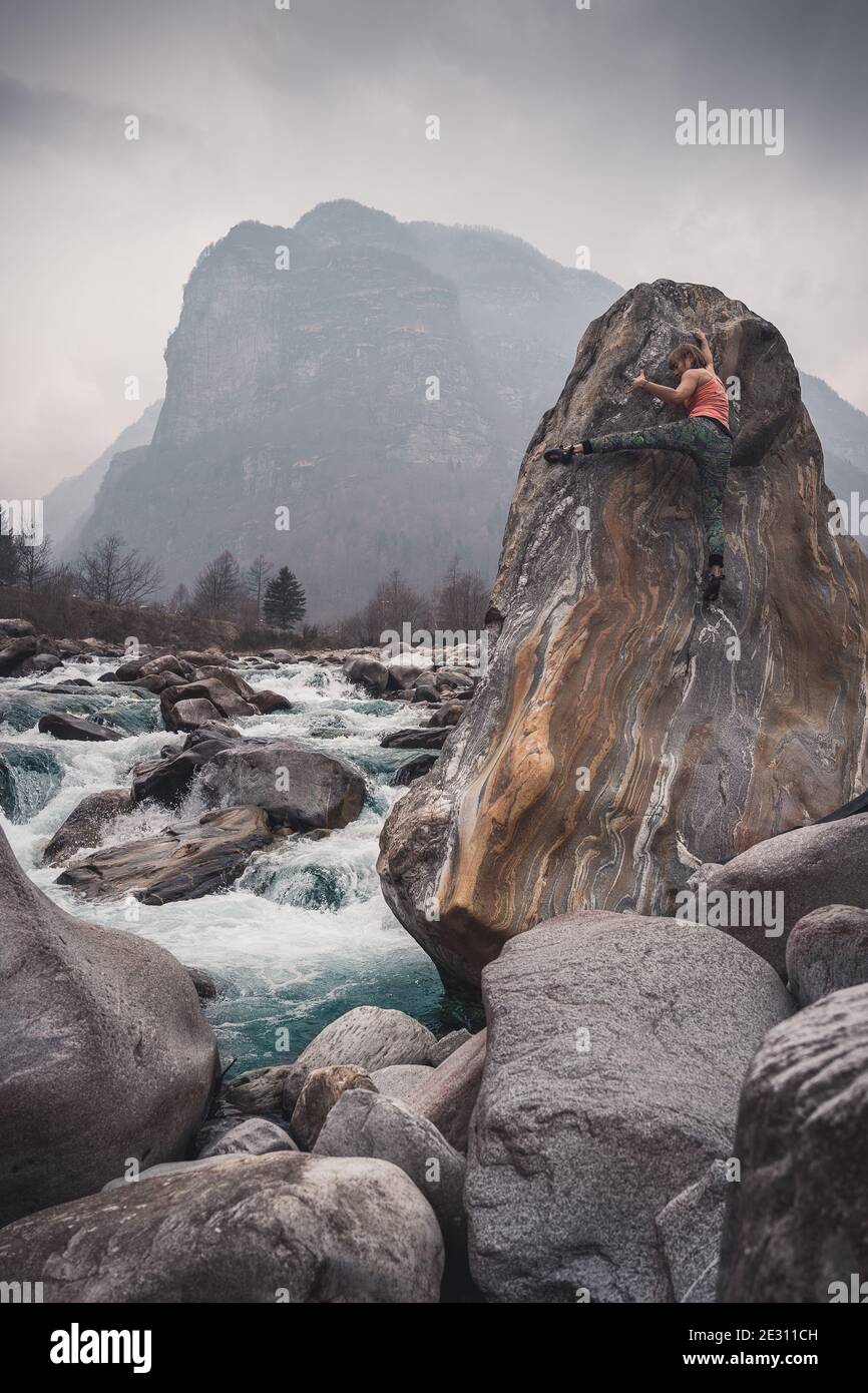 Une grimpeuse de roche femelle qui se déchète à hauteur de granit le long de la rivière Verzasca dans les Alpes suisses. Banque D'Images