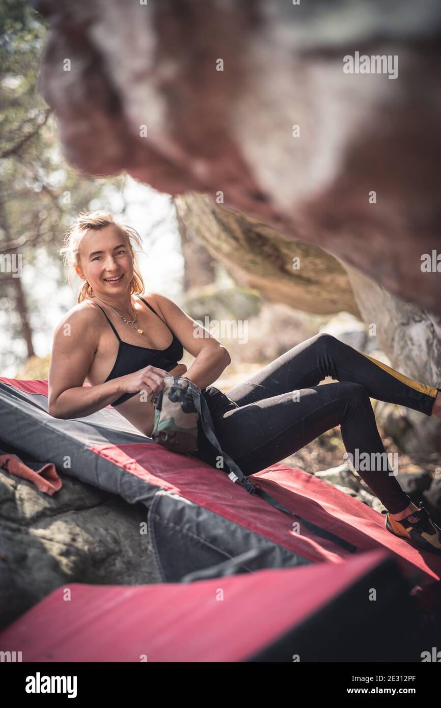 Une femme forte se préparant à gravir un rocher suspendu pendant le bloc à Fontainebleau, en France Banque D'Images