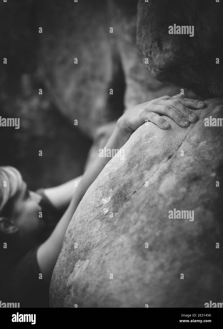 Une grimpeuse de roche femelle qui se déforme sur des rochers de grès à Fontainebleau, en France, en noir et blanc. Banque D'Images