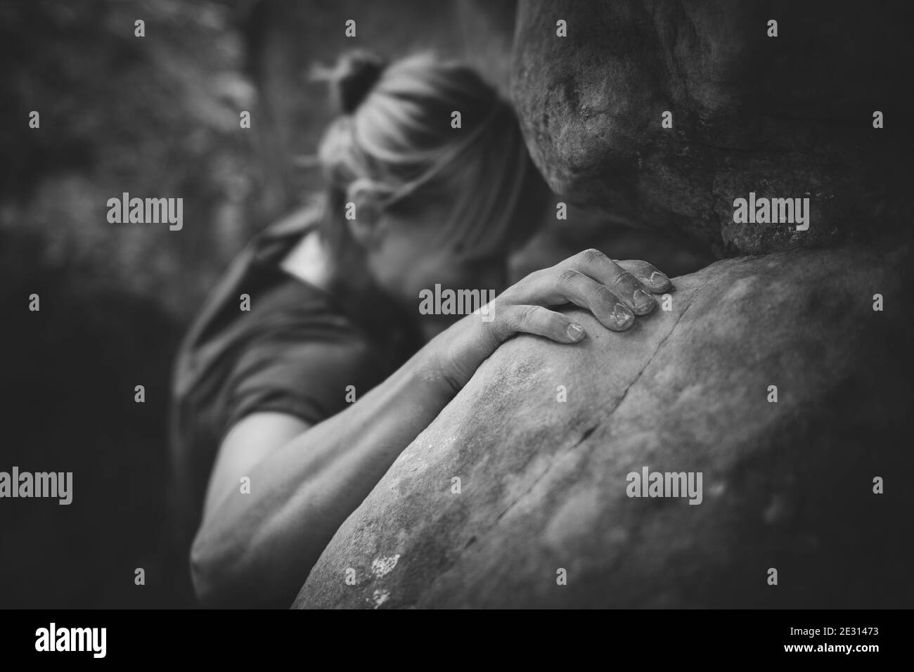 Une grimpeuse de roche femelle qui se déforme sur des rochers de grès à Fontainebleau, en France, en noir et blanc. Banque D'Images