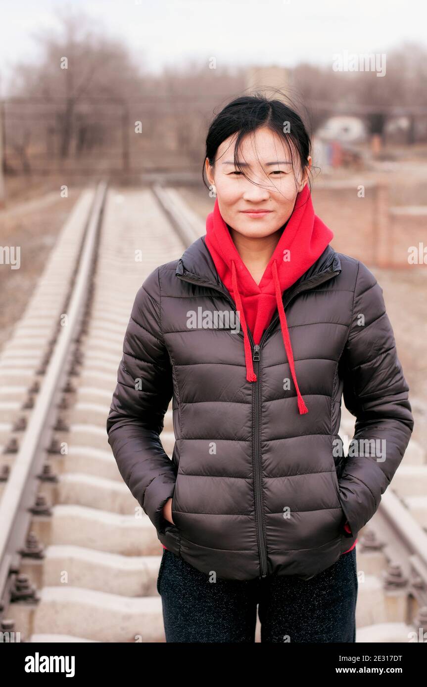 Une femme portant une veste noire et un sweat à capuche rouge debout Sur  les voies ferrées dans la ville de Zhaodong Chine dans Province de  Heilongjiang sur un froid couvert d